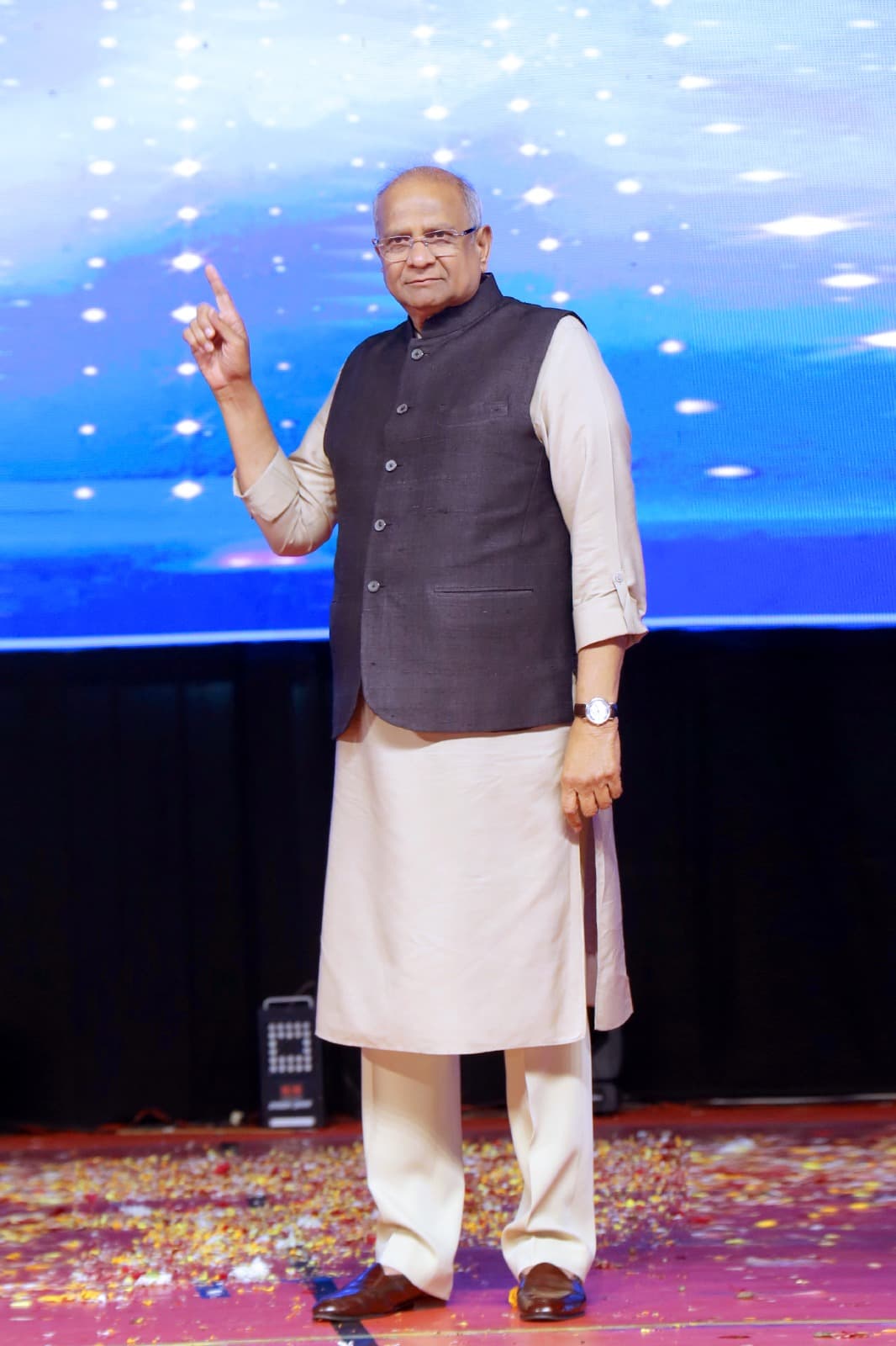 Bhupeshbhai addressing an audience from a lit stage