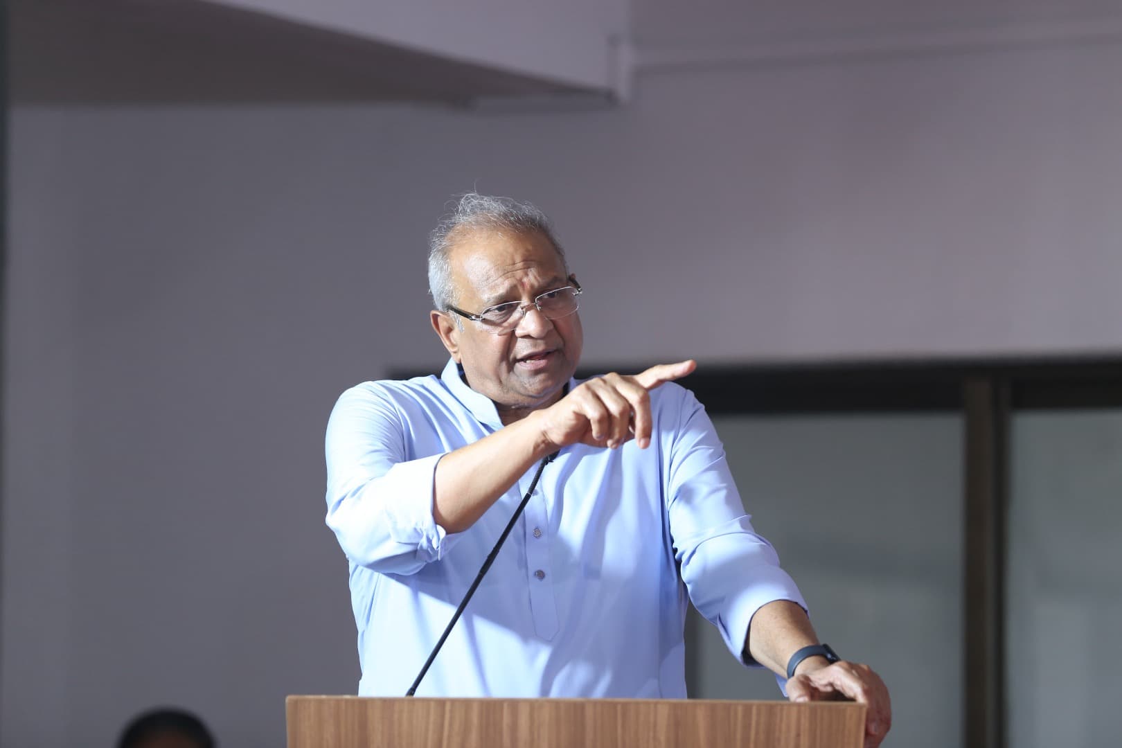 Bhupeshbhai speaking from a podium, gesturing to the audience